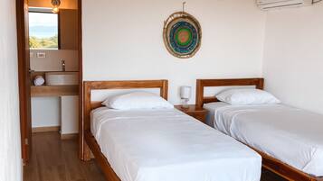 Un dormitorio con dos camas de madera, un baño pequeño y vistas al exterior.