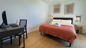 Une chambre à coucher avec un lit, un bureau avec un ordinateur et une chaise.