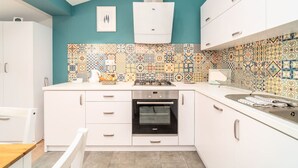A modern kitchen with white cabinets, a colorful tile backsplash, and a built-in oven.