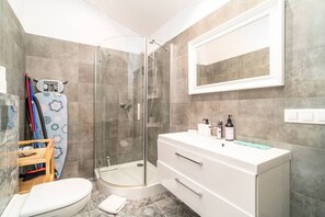 A modern bathroom with a glass shower enclosure, a white vanity with a mirror, and a toilet. - Podgórze Studio - A/C, Workdesk, Castle Nearby (Kraków)