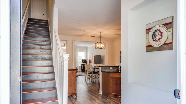 A staircase leading to a dining area with wooden flooring and a chandelier.