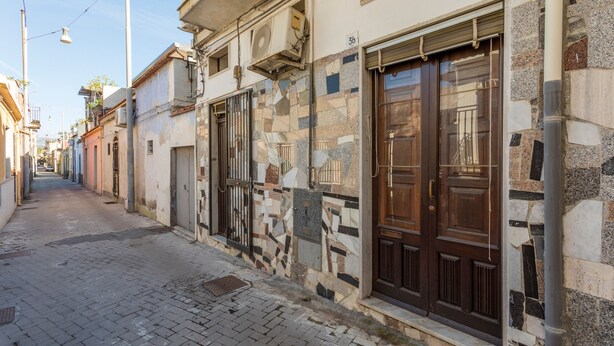 A narrow street with buildings featuring stone facades and wooden doors.