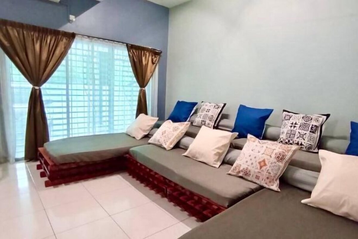 A room with a sofa set, patterned cushions, and a window with curtains.