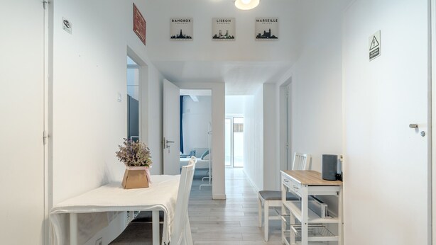 A hallway with a dining table and chairs, a small table with a plant, and a desk with a computer. - Estrela House 3 1 by Homing (Lisbon)