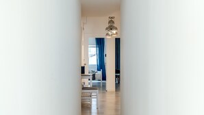 A hallway leading to a living area with a modern chandelier, a dining table, and blue curtains. - Estrela House 3 1 by Homing (Lisbon)