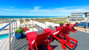 Eine Terrasse mit roten Stühlen und einem Tisch mit Blick auf Strand und Meer.