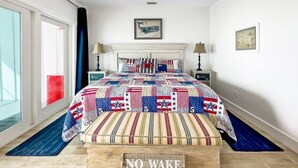 Ein Schlafzimmer mit einem großen Bett, einem Deckenventilator, einem Fenster mit Blick und einem Schild mit der Aufschrift 'NO WAKE' auf dem Boden.