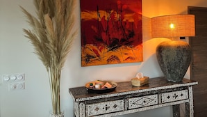 Une pièce avec un tableau accroché au mur, un grand vase et une console ornée d’objets décoratifs.