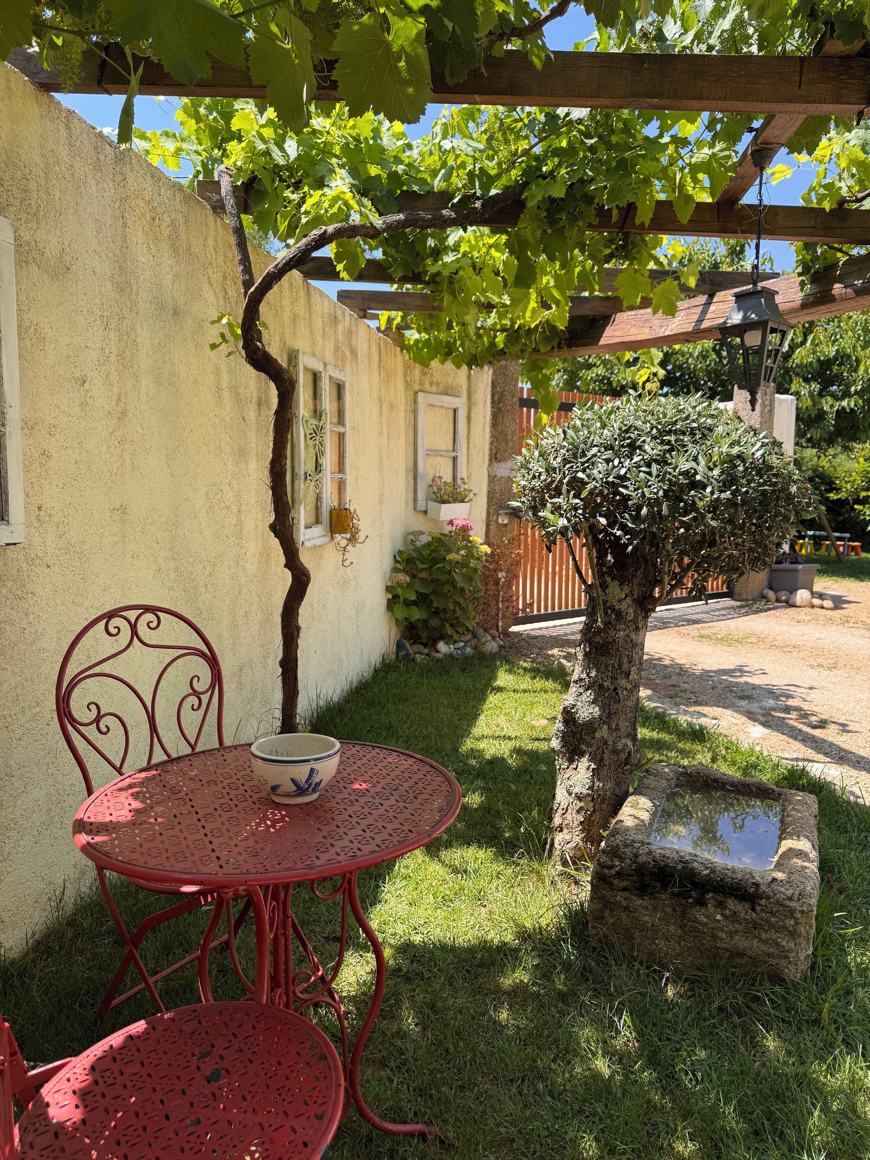 A red metal table and chair set outside a building with a pergola overhead.