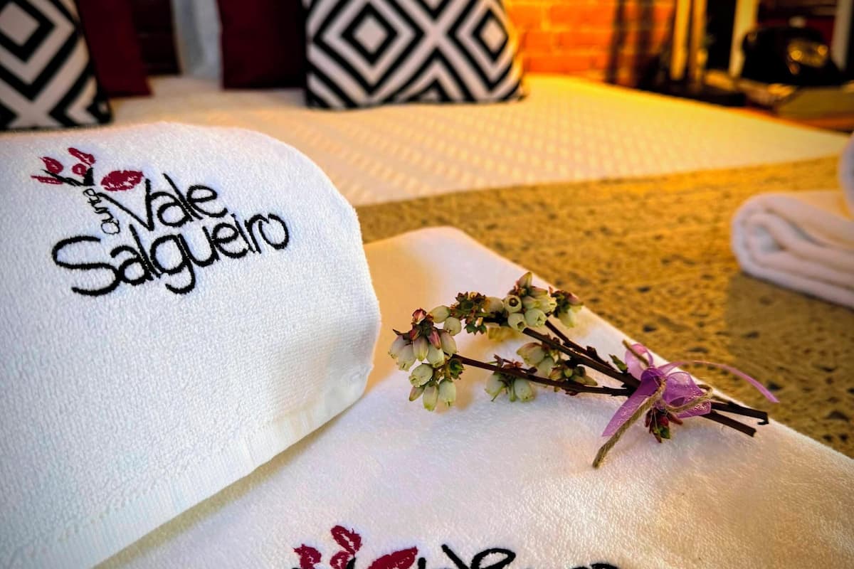 Una cama con almohadas y una toalla bordada con la frase 'Vale Salgueiro'.