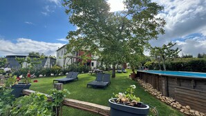 A backyard with a swimming pool, lounge chairs, a wooden deck, and a garden area. - Quinta Vale Salgueiro (Carragozela)