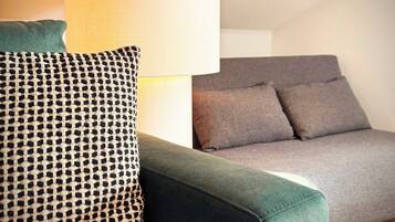 Uma sala de estar moderna com um sofá verde, uma almofada decorativa estampada e um sofá cinzento.