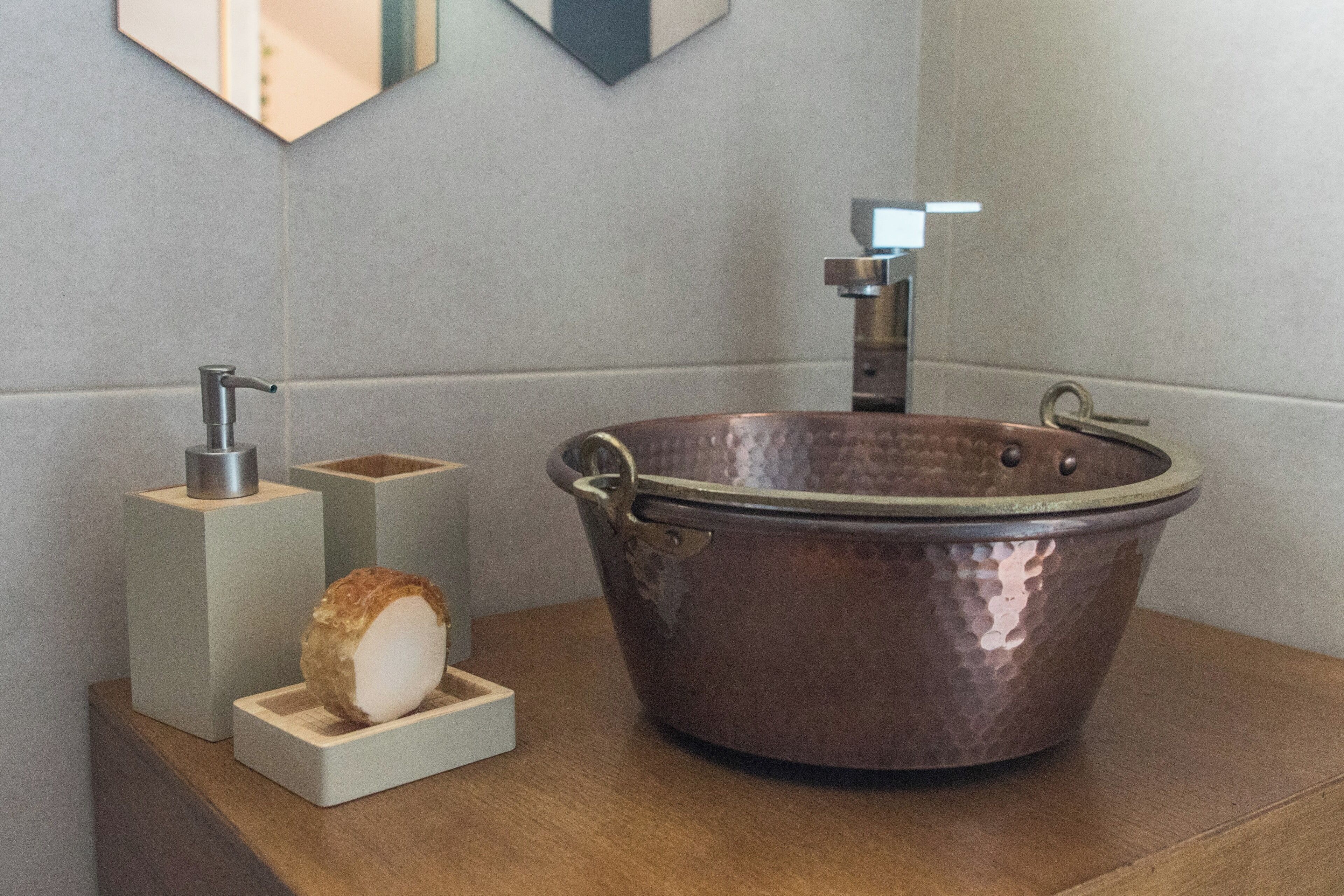 Un bagno con una bacinella in rame, un erogatore di sapone e un saponiera in legno.