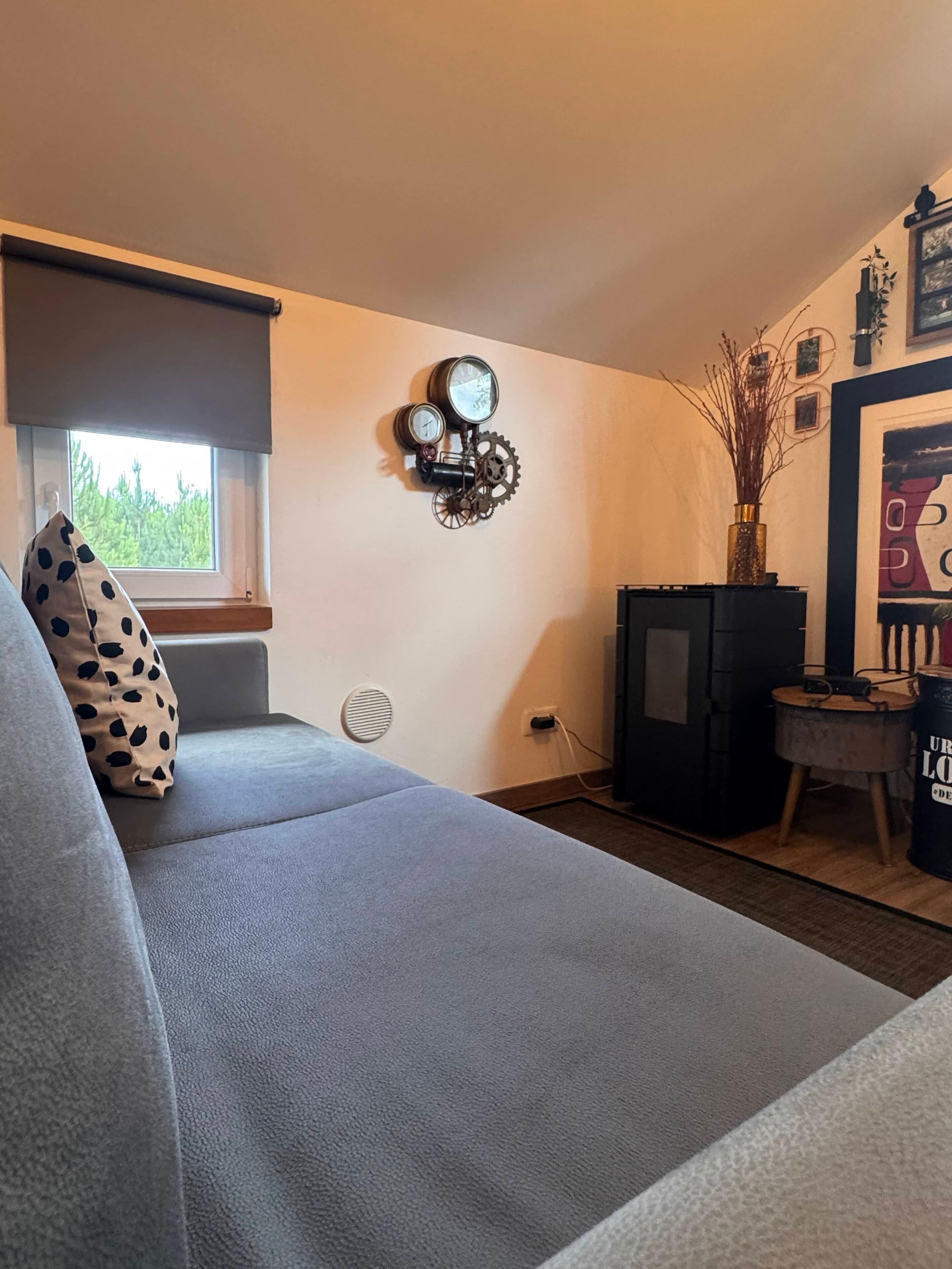 Ein Zimmer mit einem Bett, einer Wanduhr, einem Heizkörper und einem kleinen Tisch mit einer Vase.