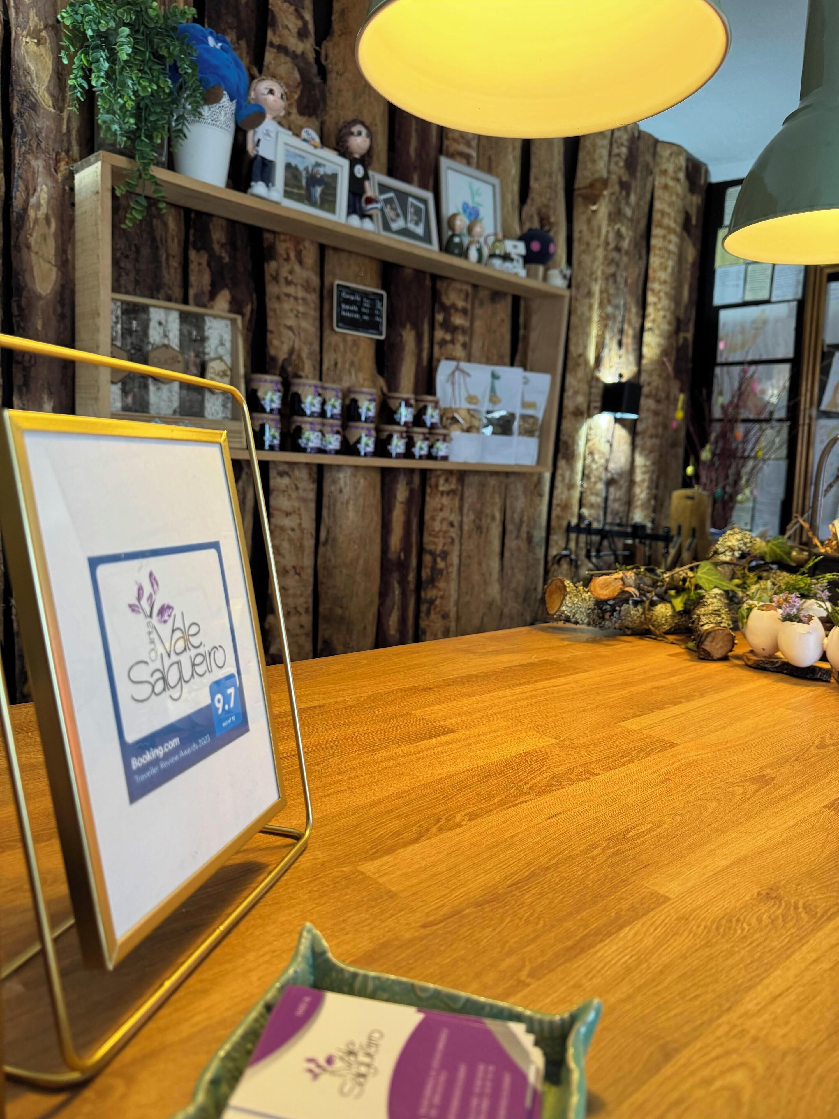 A wooden reception desk with a framed award sign, a small plant, and a shelf with framed photos and decorative items.