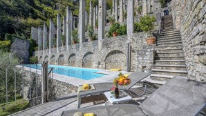 A stone staircase leading to a pool area with lounge chairs and a table with fruit and a drink. - Lemon Garden Retreat - Villa Aqua (Gargnano)