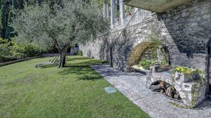 A stone building with a stone fireplace, a grassy lawn, and a tree. - Lemon Garden Retreat - Villa Aqua (Gargnano)