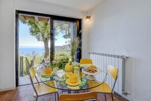 A dining area with a glass table and yellow chairs, overlooking a scenic view.