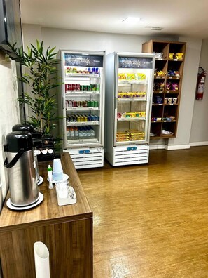 Zwei Getränkespender mit verschiedenen Getränken, eine Kaffeemaschine und ein kleiner Tisch mit Tassen und einer Flasche.