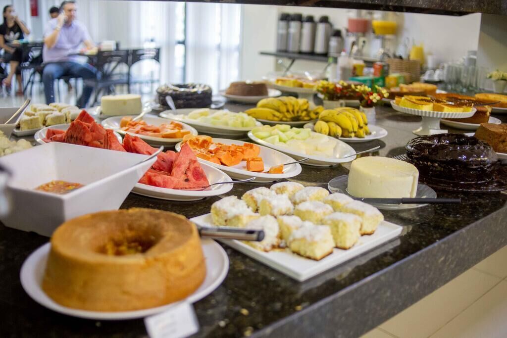 A buffet with various food items including fruits, pastries, and a cake.