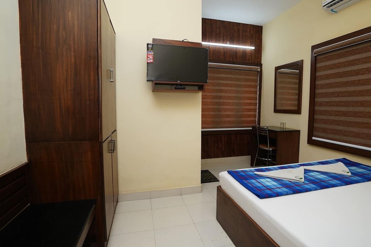 A bedroom with a bed, a desk, a chair, a television, and a wardrobe.