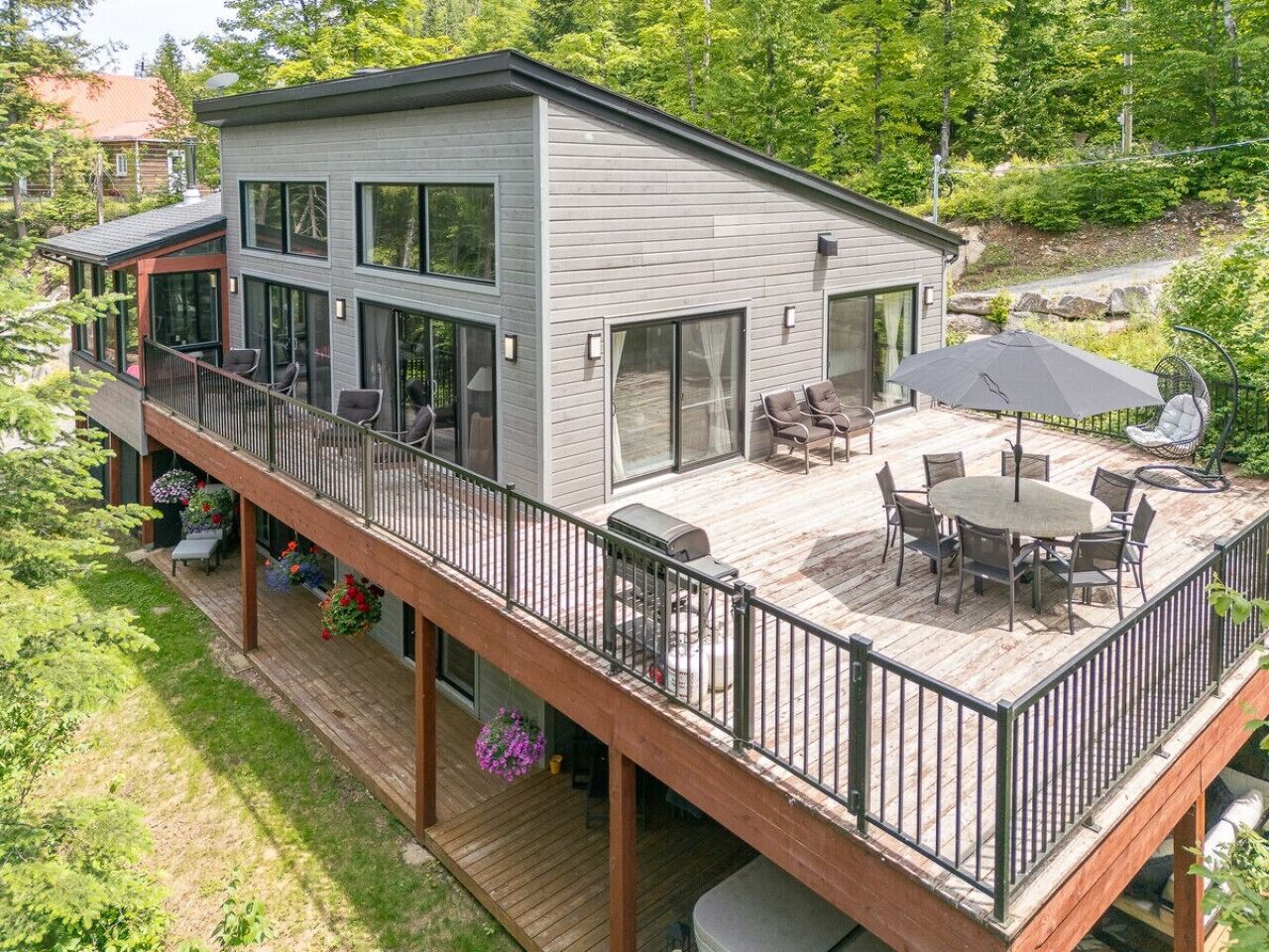 Een modern huis met twee verdiepingen, een terras, tuinmeubilair en een barbecue.