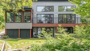 Een modern huis met twee verdiepingen, grote ramen, een balkon en een tuin.