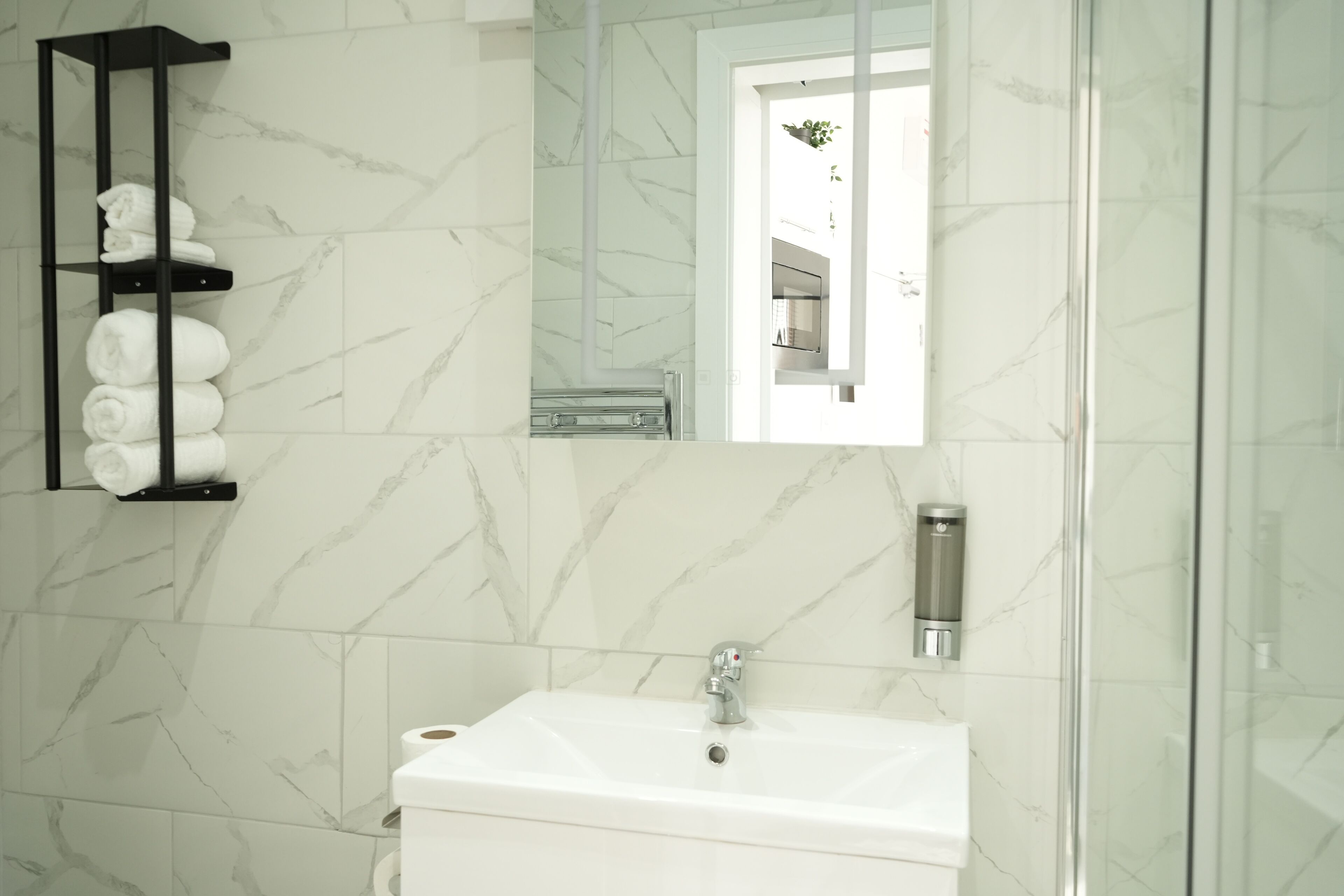 A bathroom with a white sink, a towel rack, a mirror, and a glass shower enclosure.