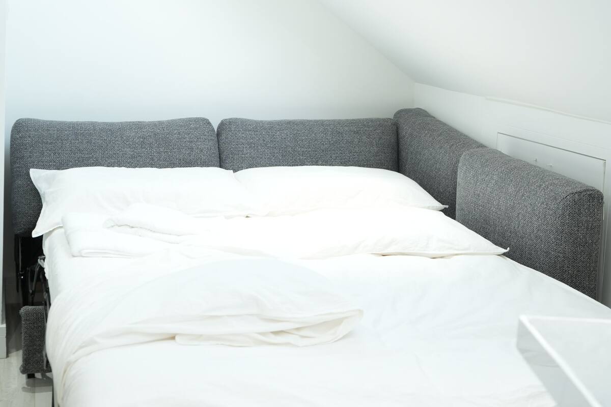 A modern, compact room with a bed, skylight, and minimalistic design.
