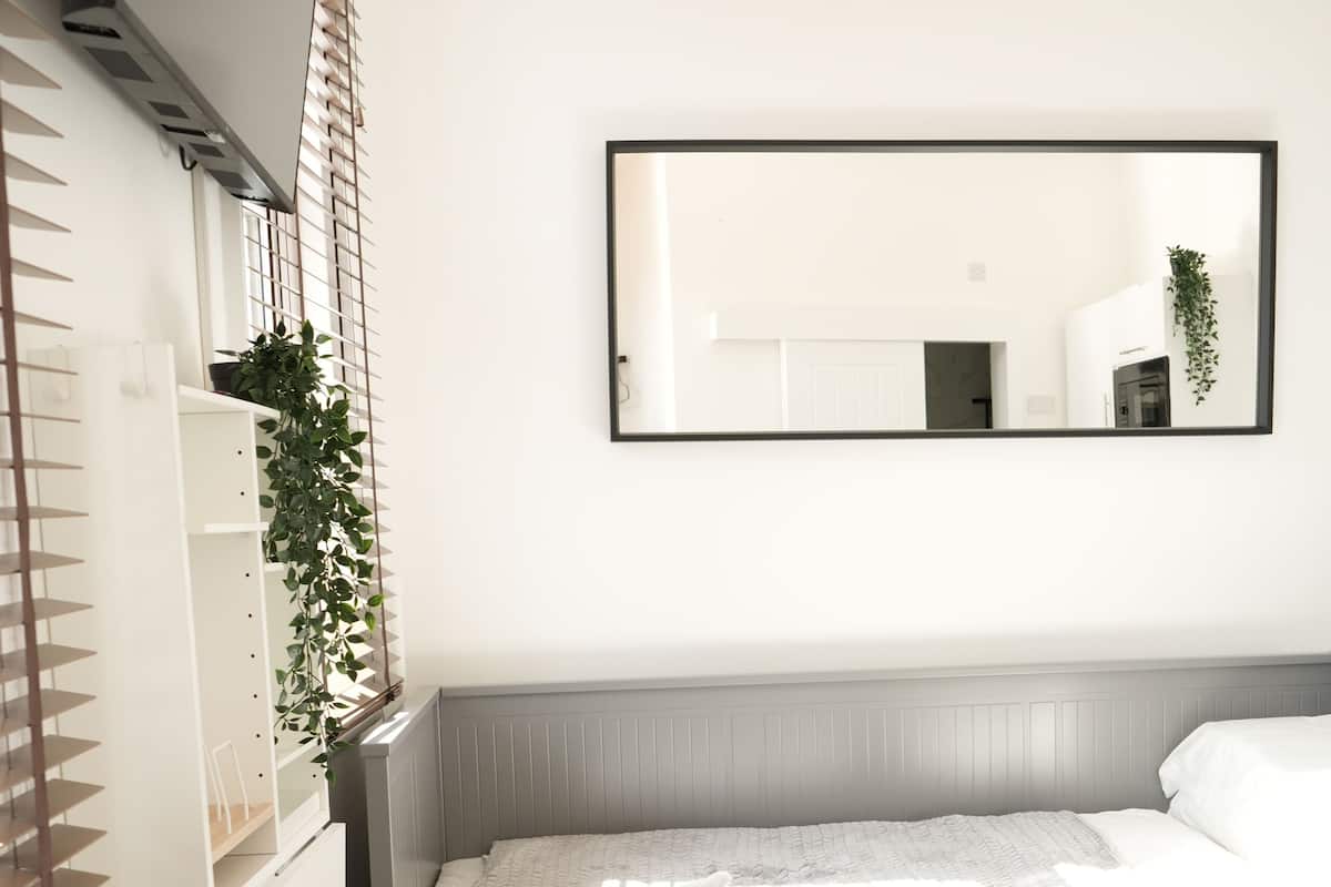 A bedroom with a bed, a dresser, a mirror, and a radiator.