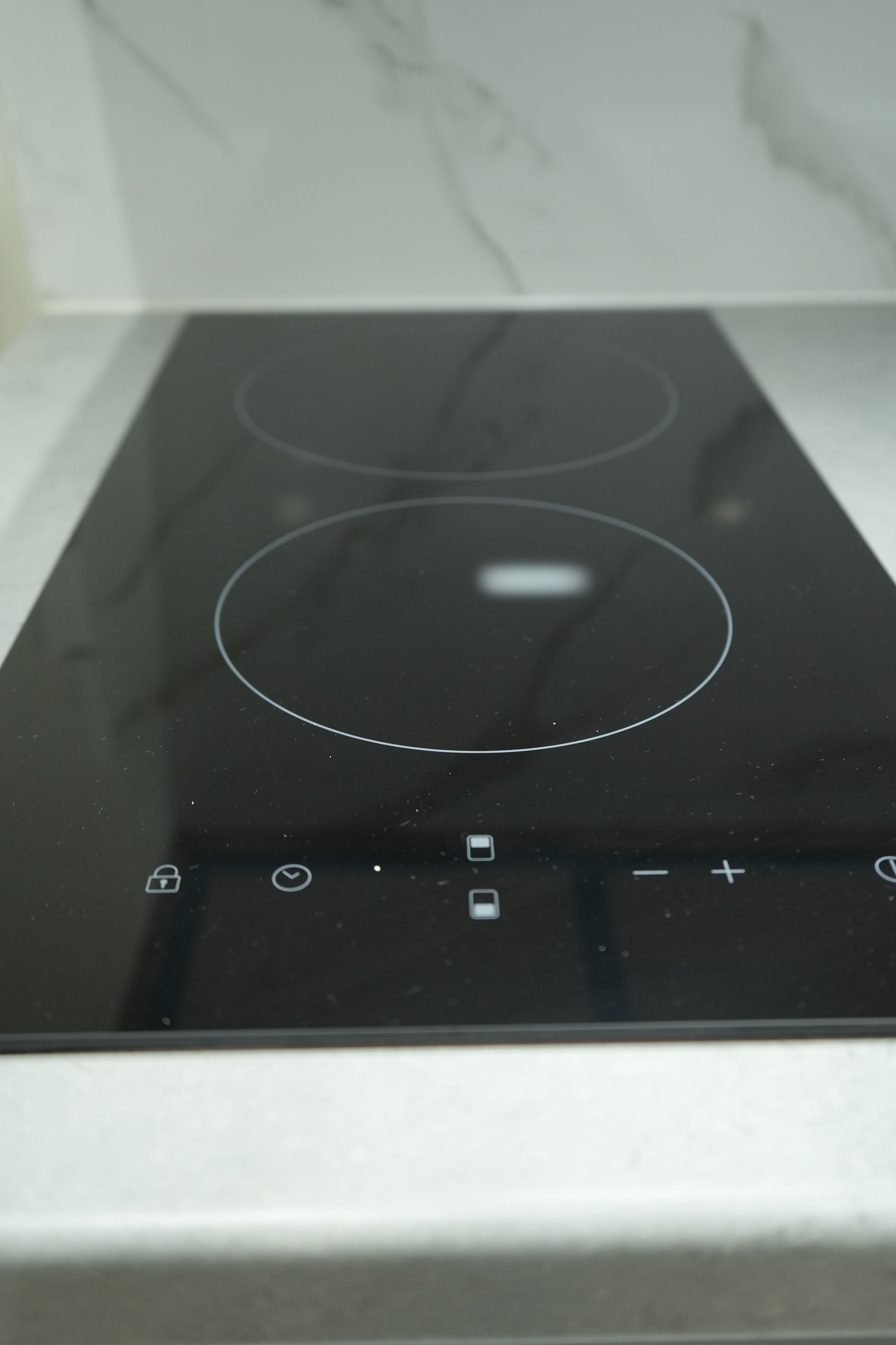 A black induction cooktop with control buttons and a digital display.