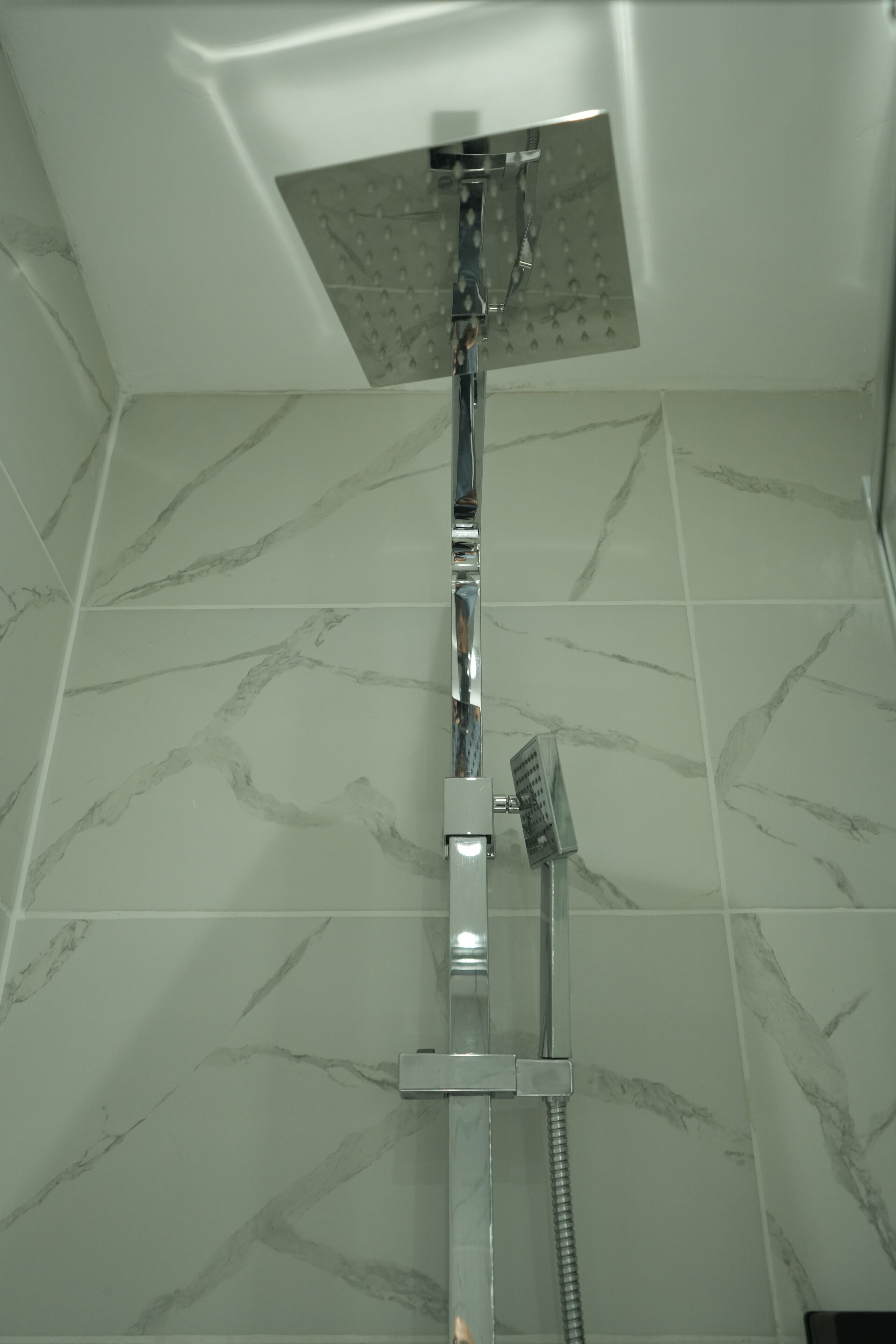 A shower with a square head and a handheld showerhead.