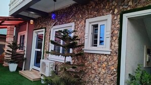 Un edificio con paredes de piedra, ventanas con marcos blancos y plantas en macetas.