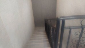 Una escalera estrecha con barandilla metálica, que conduce a un rellano.