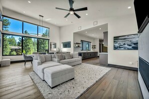 A modern living room with a sectional sofa, a dining area, and a kitchen.
