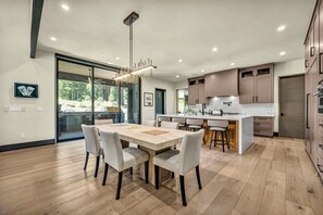 A modern kitchen with a central island, wooden flooring, and a dining area with a table and chairs.