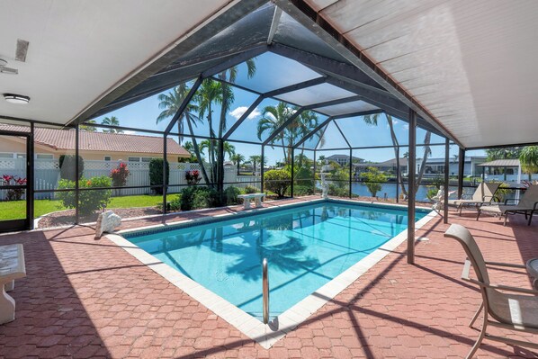 Une piscine couverte offrant une vue sur des palmiers et un plan d’eau.