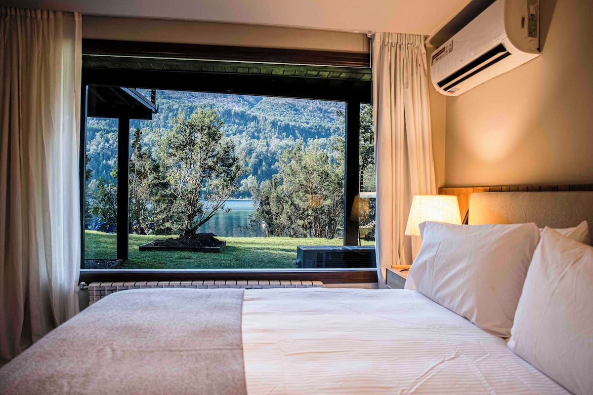 Ein Hotelzimmer mit einem großen Bett, einem Fenster mit Vorhängen und einer Klimaanlage.