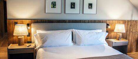 A neatly made bed with white linens, two bedside tables with lamps, and three framed pictures on the wall above the bed.