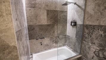 Un baño moderno con ducha de vidrio, bañera blanca y azulejos de mármol.