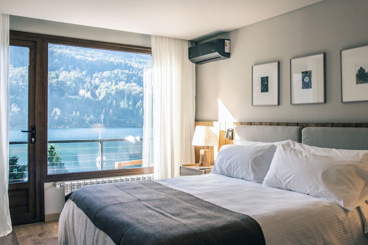 Ein Hotelzimmer mit einem großen Bett, Meerblick und gerahmten Bildern an der Wand.