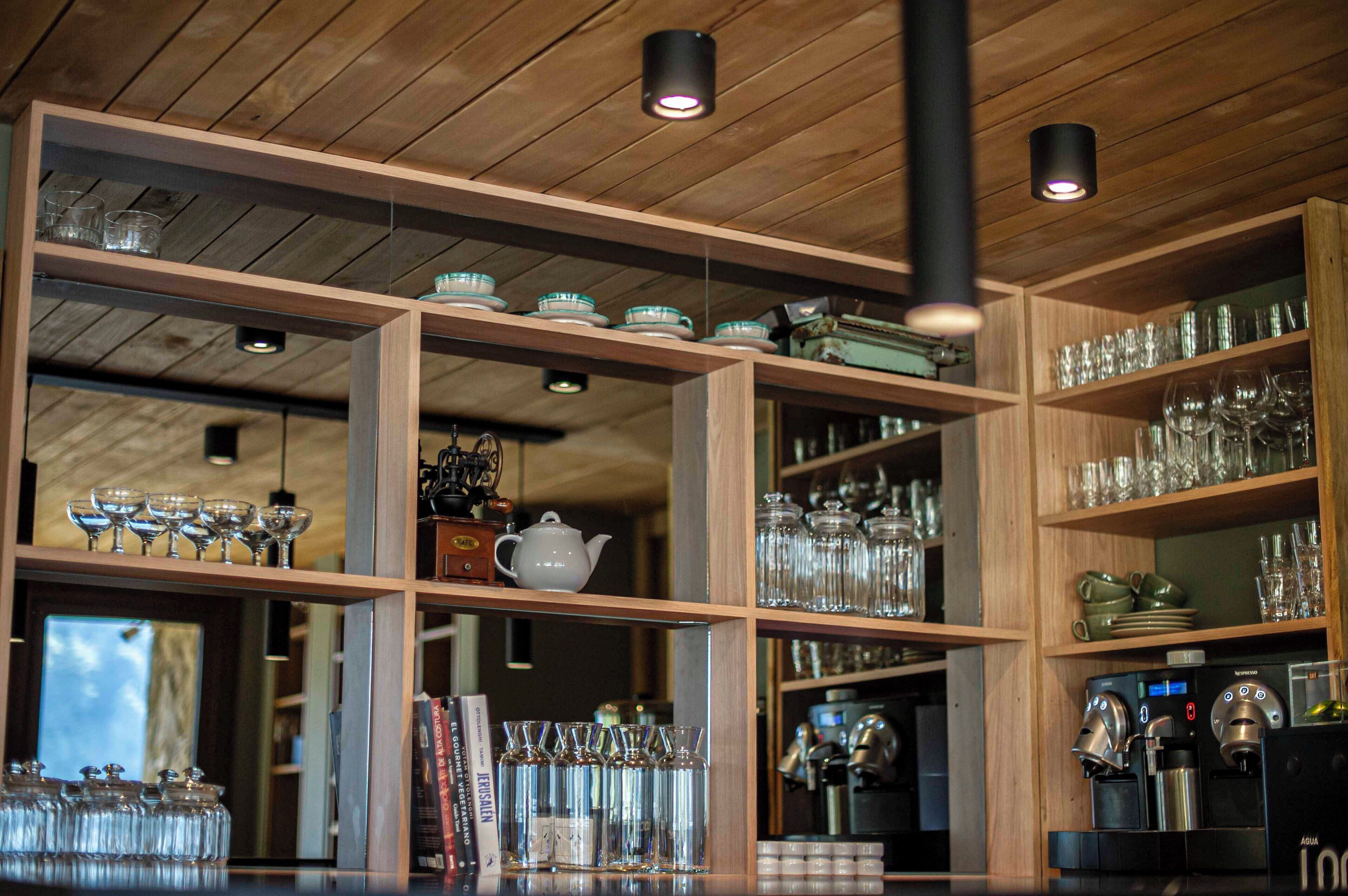 A bar area with shelves of glassware and a coffee machine.