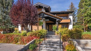 A modern building with a covered entrance, a stone staircase, and a landscaped garden with various plants and flowers.