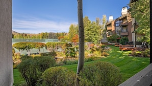 A residential area with a well-maintained lawn, a tennis court, and a view of a lake.