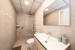 Un bagno moderno con doccia vetrata, un water bianco e un mobile lavabo con uno specchio grande.