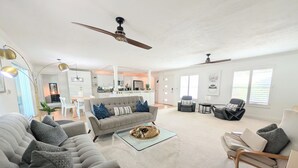 A spacious living room with a grey sofa, a coffee table, and a ceiling fan.