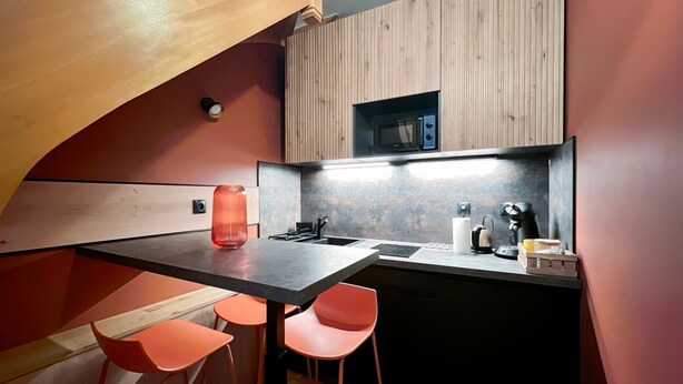 A compact kitchen with a wooden countertop, a sink, a microwave, and two orange chairs. - Beautiful Souplex - 2P - Nation (Paris)
