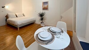 A compact room with a bed, a dining table set with plates, glasses, and a vase.