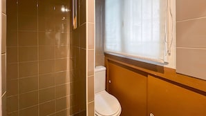 A bathroom with a shower, toilet, and a window.