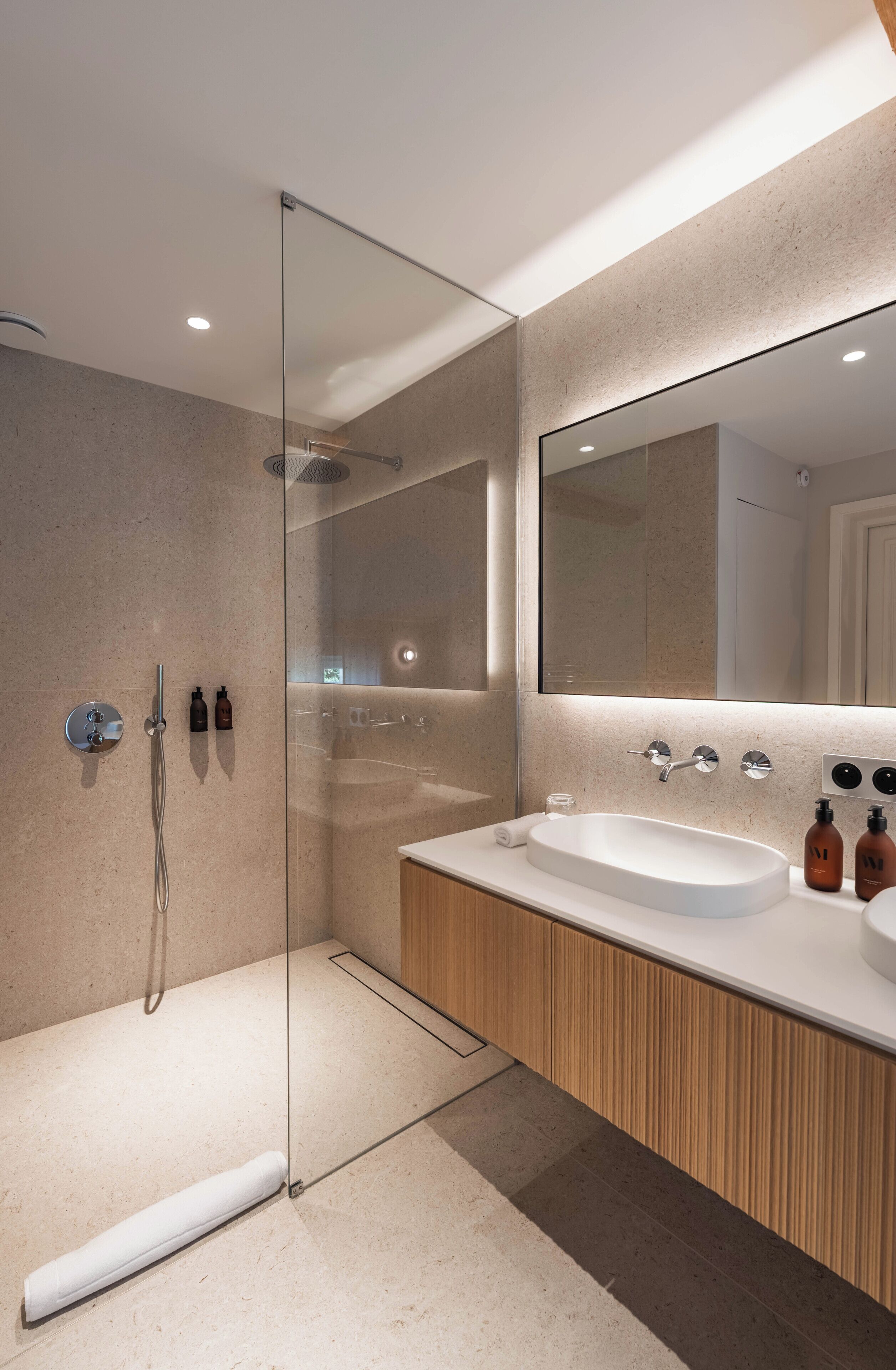Un bagno moderno con cabina doccia in vetro, uno specchio grande e un mobile bagno in legno con lavandino.